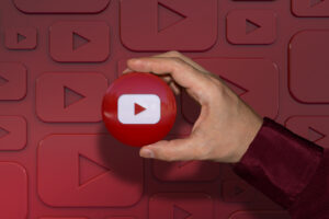 canal no youtube mão segurando logotipo fundo vermelho